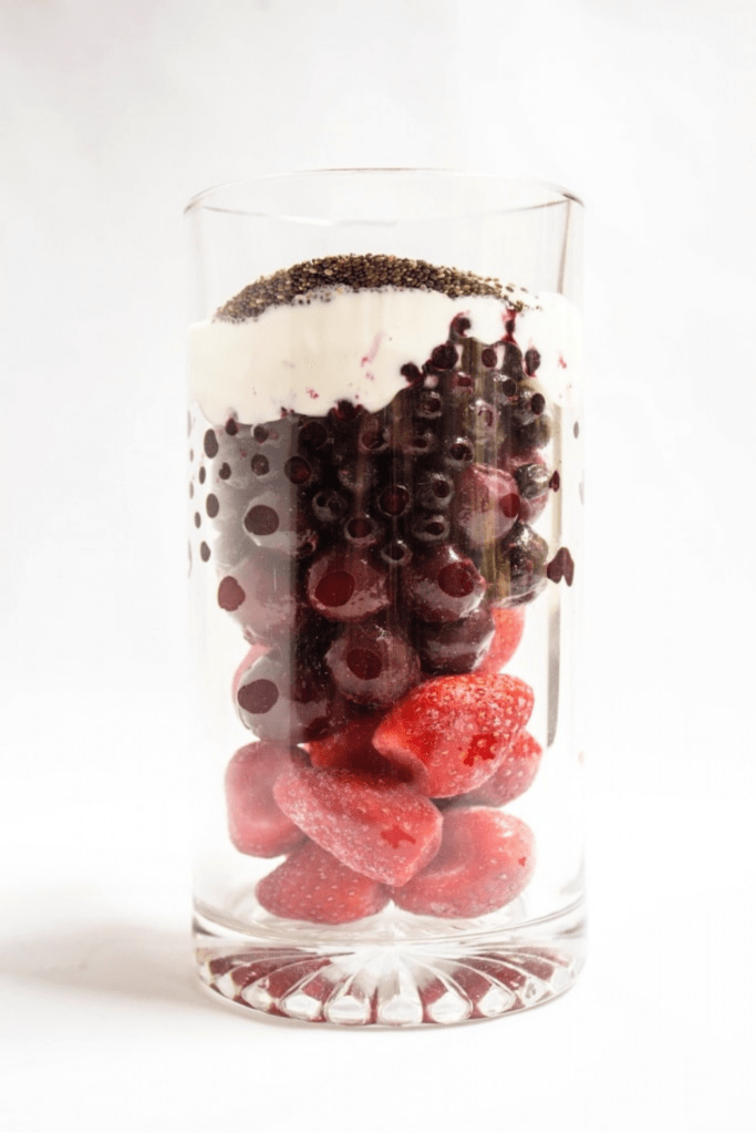 berry smoothie ingredients with yogurt and chia seeds in a tall glass