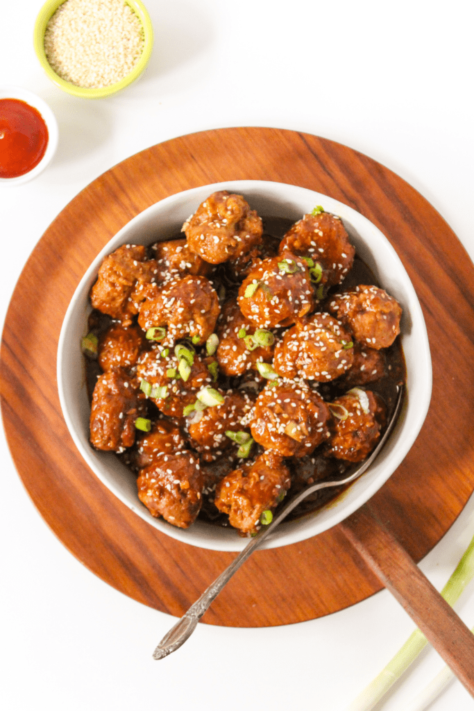 crockpot turkey meatballs in a large white bowl with scallions and sesame seeds