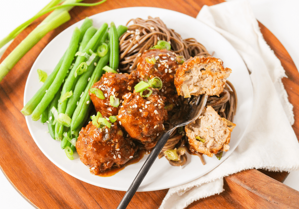 asian meatballs with green beans and soba noodles on a plate