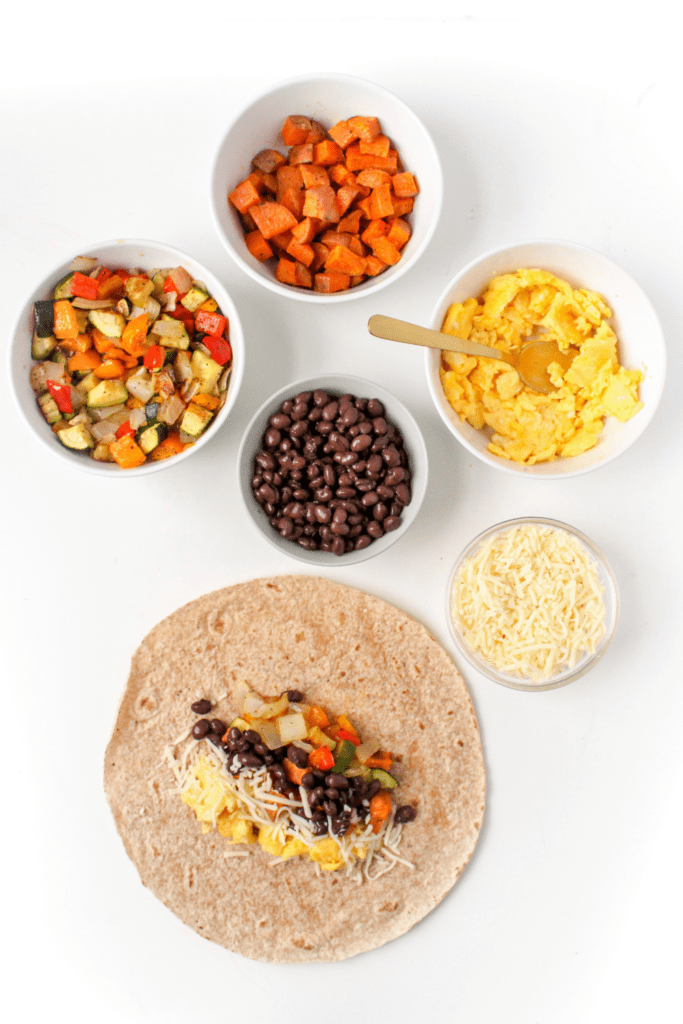 vegetarian breakfast burritos ingredients in small bowls next to a large tortilla