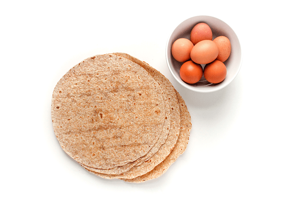 breakfast burrito ingredients: a stack of tortillas next to a bowl of eggs