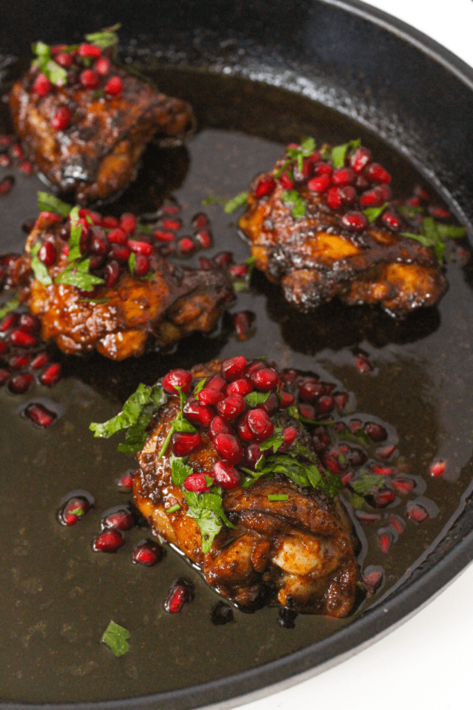 pan seared chicken thighs with pomegranate glaze on a skillet