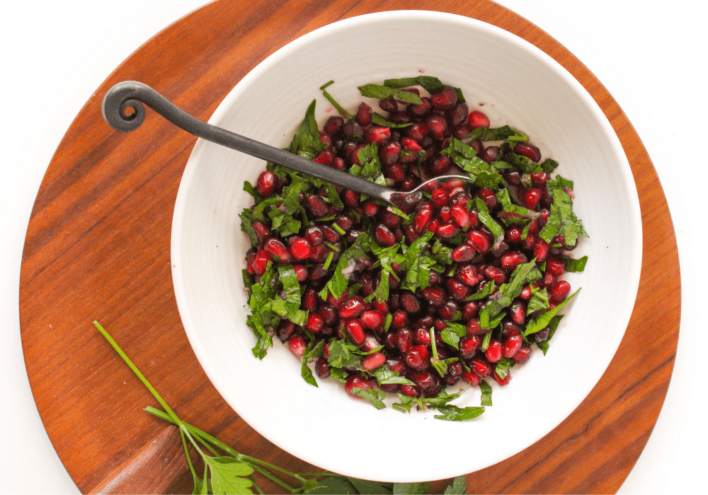 pomegranate seeds with herbs in a white bowl