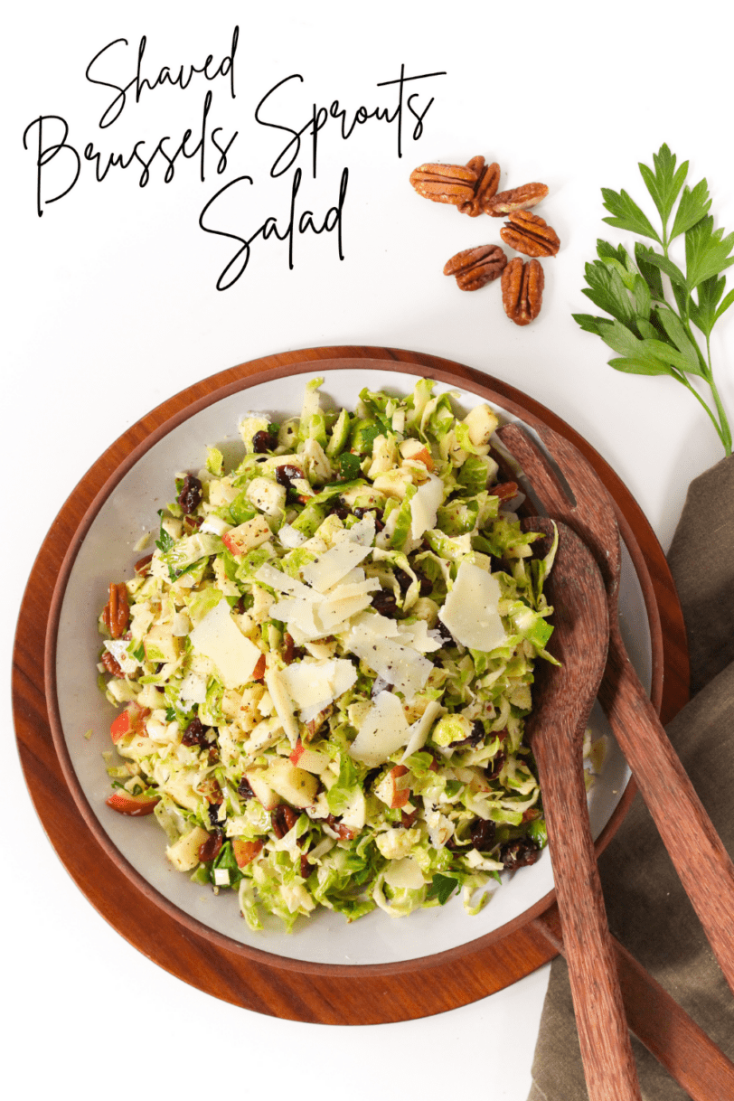 shaved brussels sprouts salad in a bowl with wooden spoons