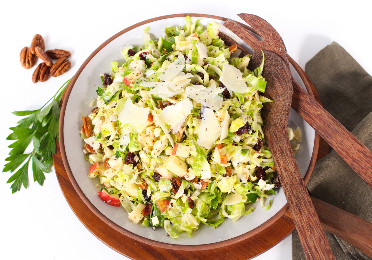 shaved brussels sprouts salad in a wide bowl with wooden salad forks
