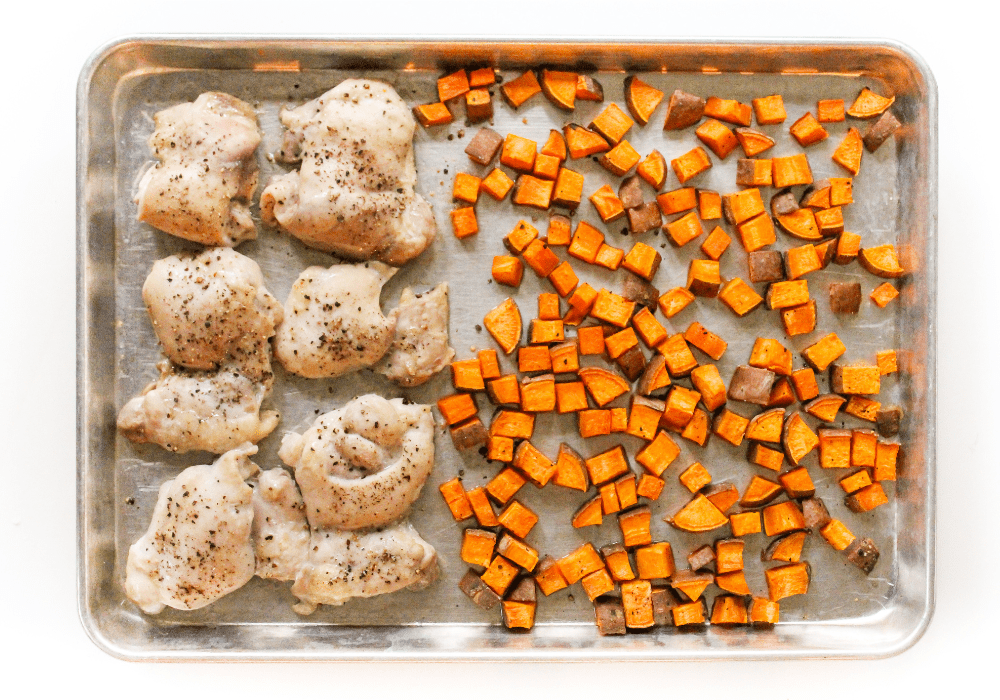 diced sweet potatoes and chicken thighs on a sheet pan