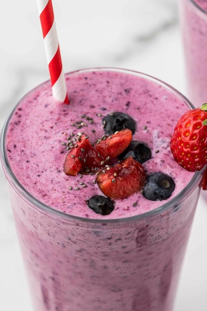 fruit smoothie with chia seeds and berries in a glass with a striped straw