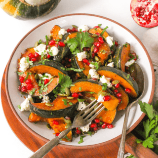 roasted buttercup squash on a plate with goat cheese and pomegranate seeds