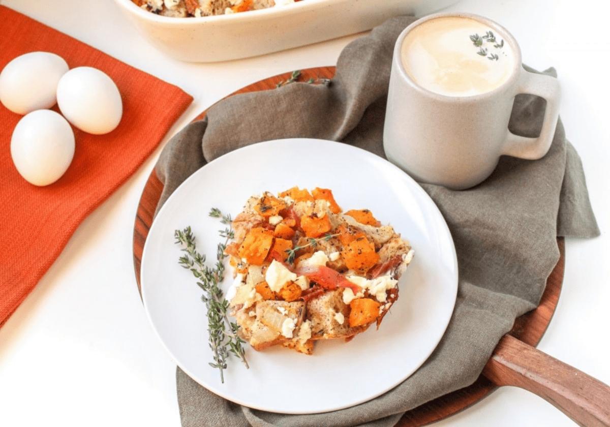 autumn strata with prosciutto and goat cheese next to a grey coffee mug