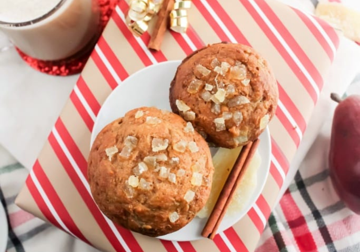 pear muffins topped with candied ginger, sitting on a plate on top of presents wrapped in striped paper