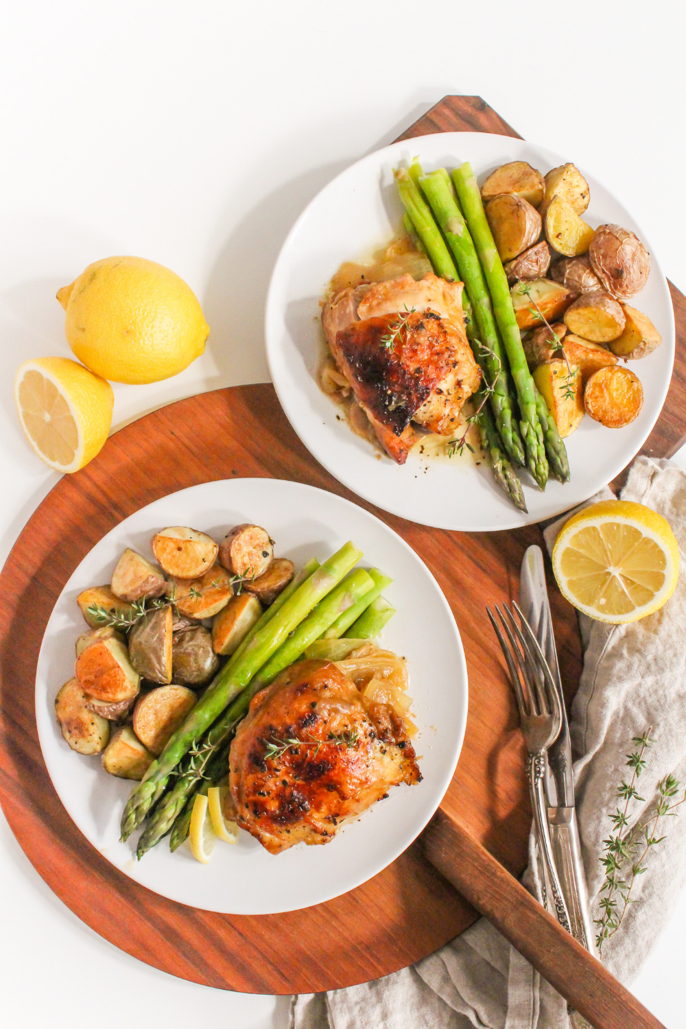 roasted chicken thighs, potatoes, and asparagus on a plate with lemons