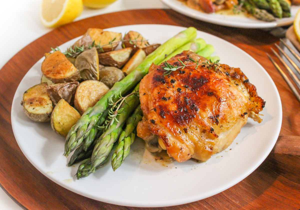 crockpot honey lemon chicken in a plate with asparagus and roasted potatoes