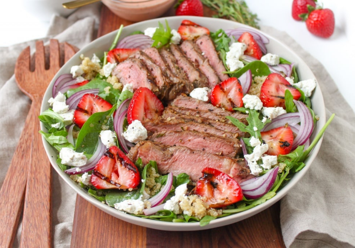 steak and strawberry goat cheese  salad with wooden salad spoons