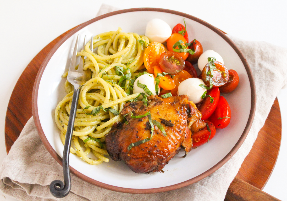 plate of chicken thighs, spaghetti, and caprese salad