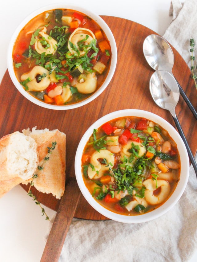 vegetarian tortellini soup in two bowls with crusty bread