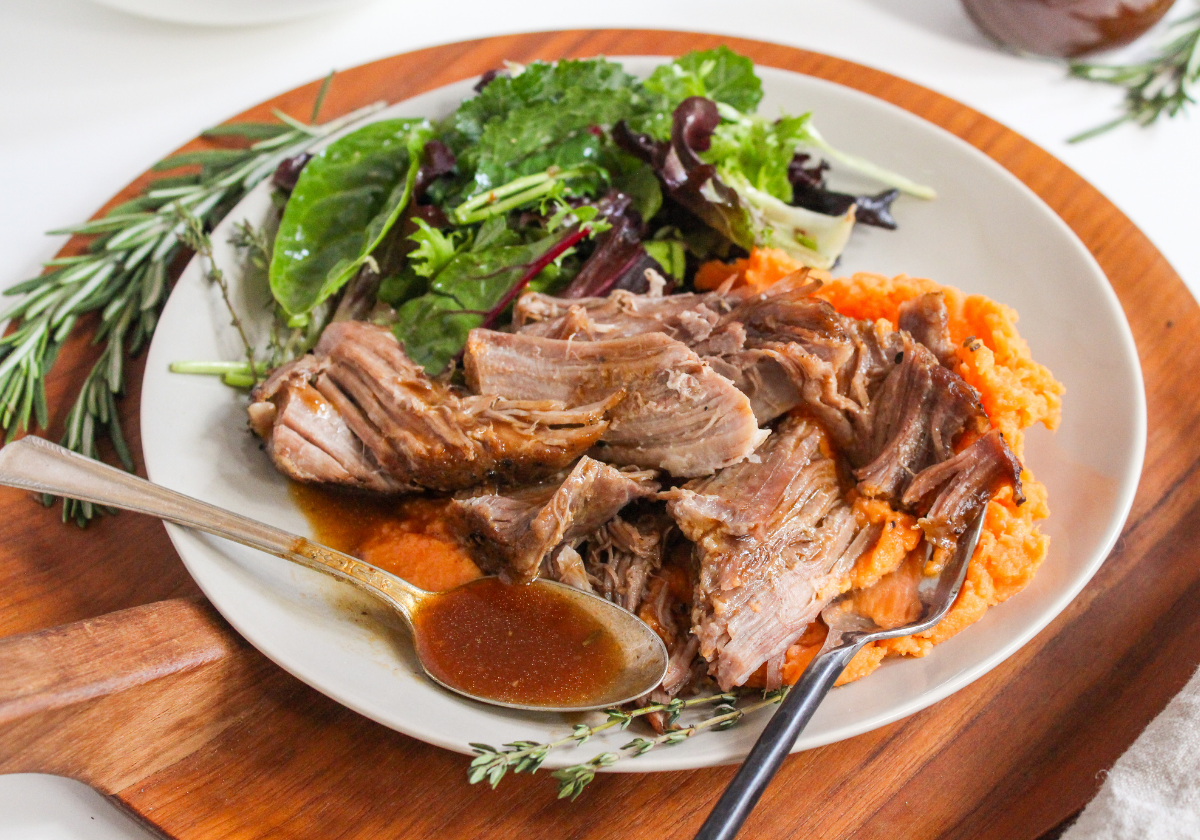 pressure cooker pork shoulder on a plate with mashed sweet potatoes and a green salad