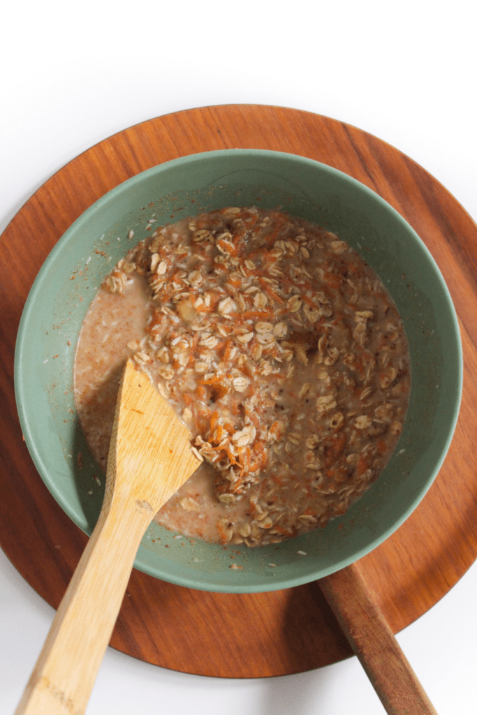 carrot cake overnight oats in a large bowl with a wooden spoon