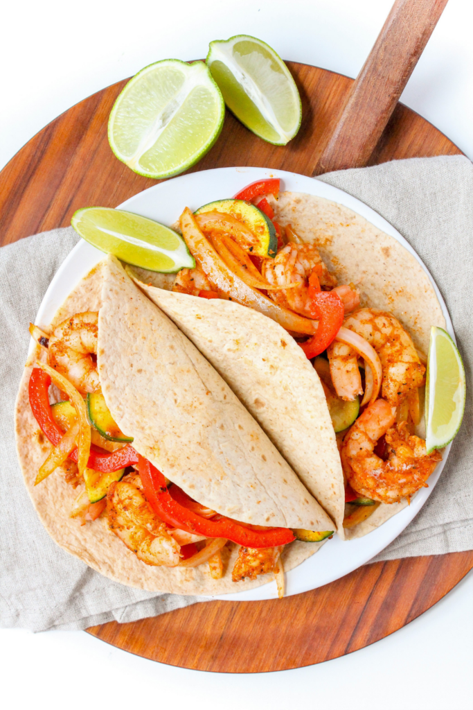 shrimp fajitas with sliced lime on a white plate