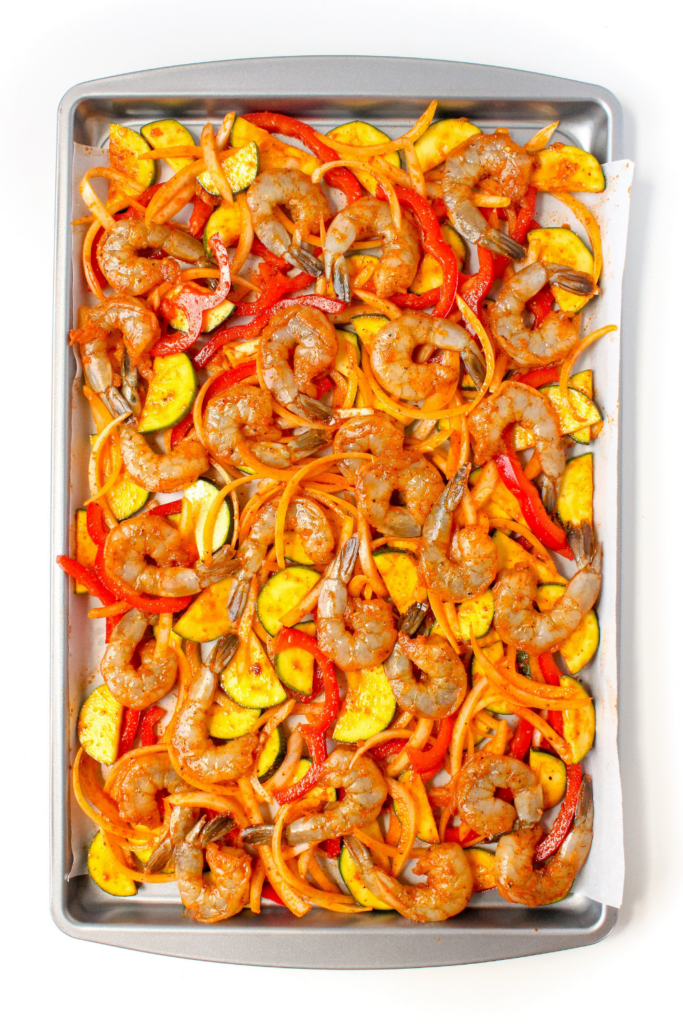 raw shrimp and vegetables on a sheet pan