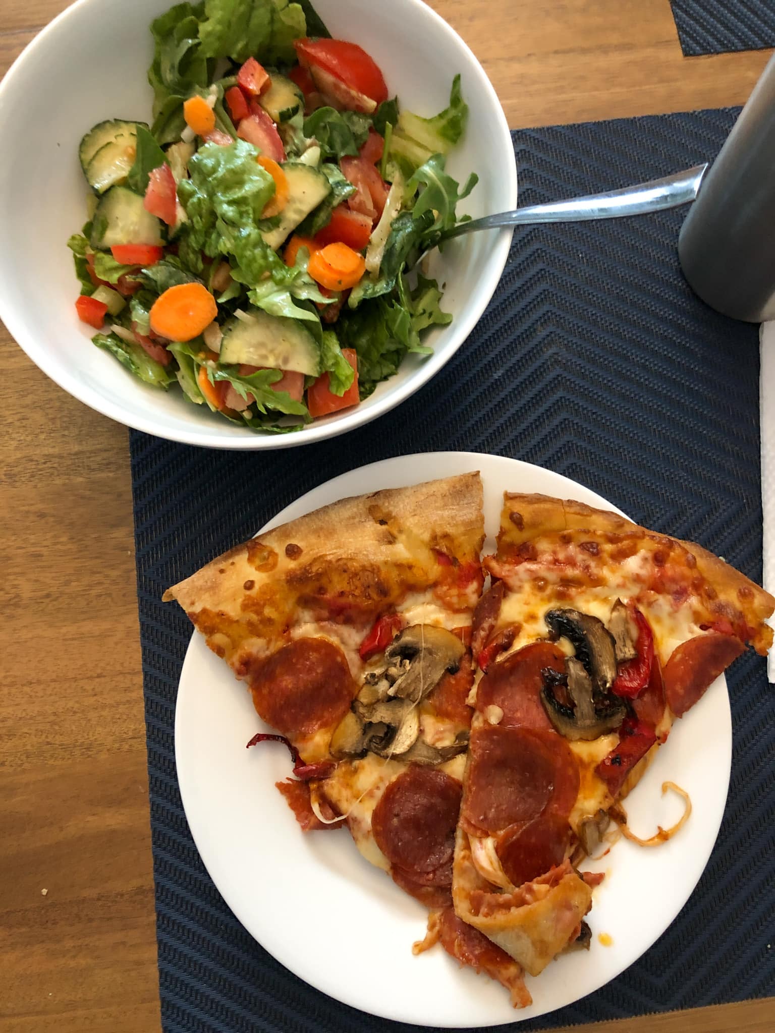 pizza on a plate and salad in a bowl.
