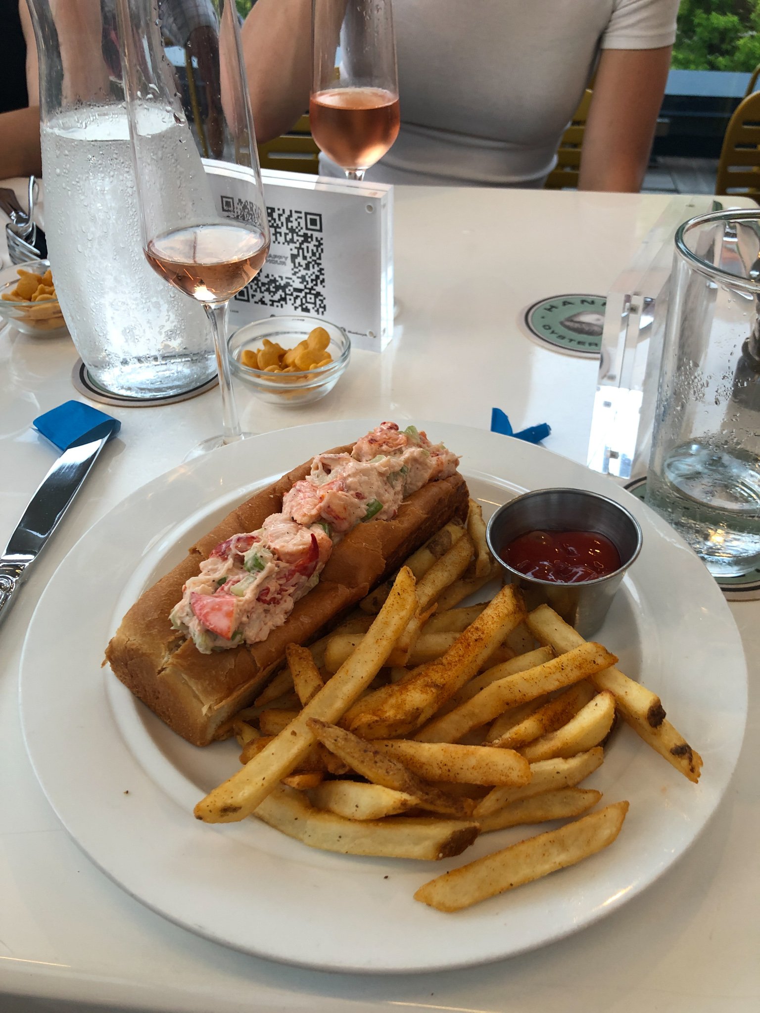lobster roll on a plate with french fries.