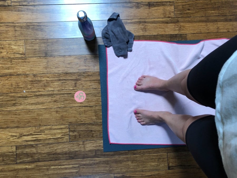 standing on a yoga mat with a towel