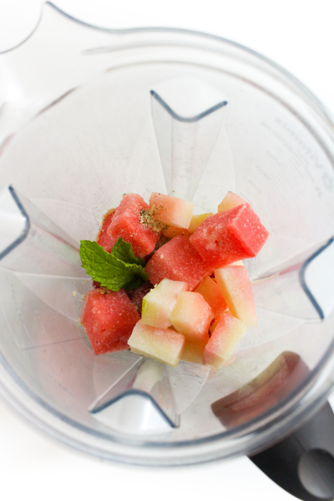 frozen fruit in a blender with fresh mint