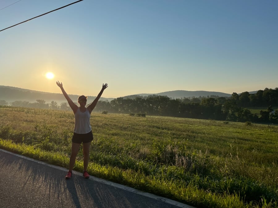 anne mauney standing on a rural road with the sun rising