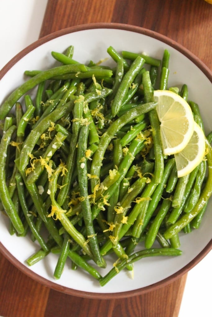 roasted green beans in a large bowl with lemon slices