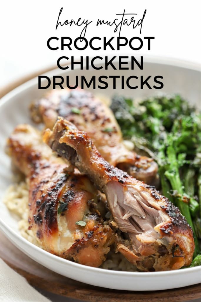 Slow cooker chicken drumsticks with honey mustard sauce in a shallow dish with broccolini