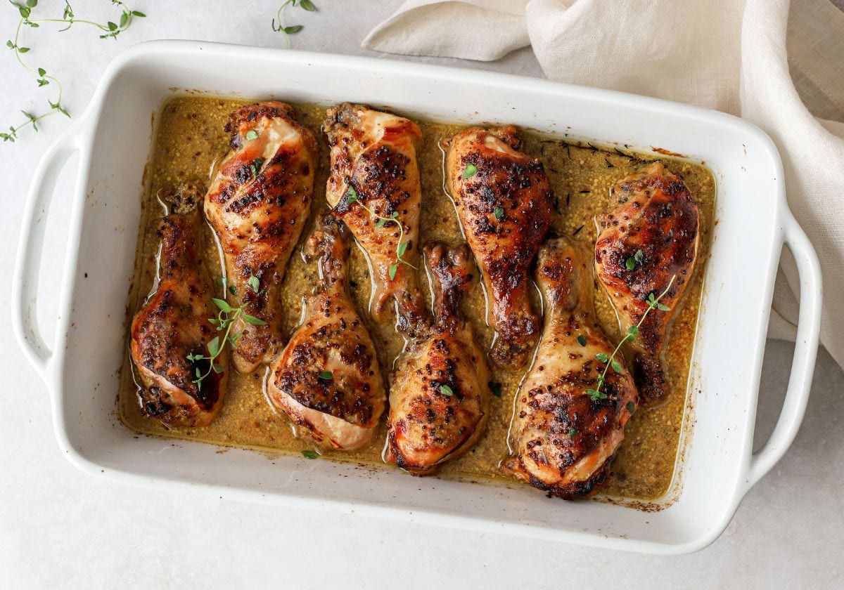 chicken drumsticks with honey mustard sauce in a white baking dish