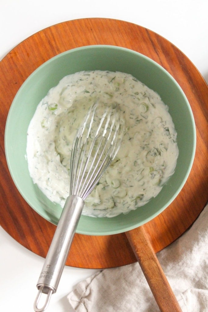 greek yogurt herb mixture in a bowl with a whisk