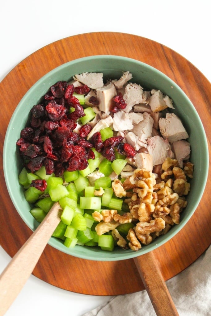 cubed chicken, dried cranberries, celery, and walnuts in a bowl