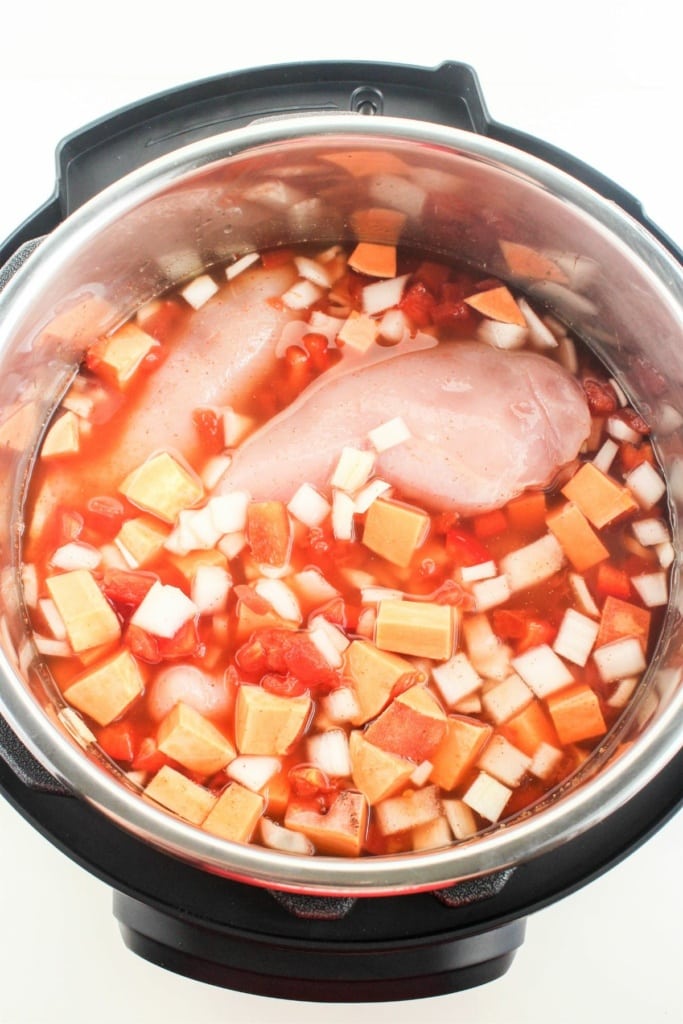 diced vegetables, chicken breasts, and broth in a pressure cooker