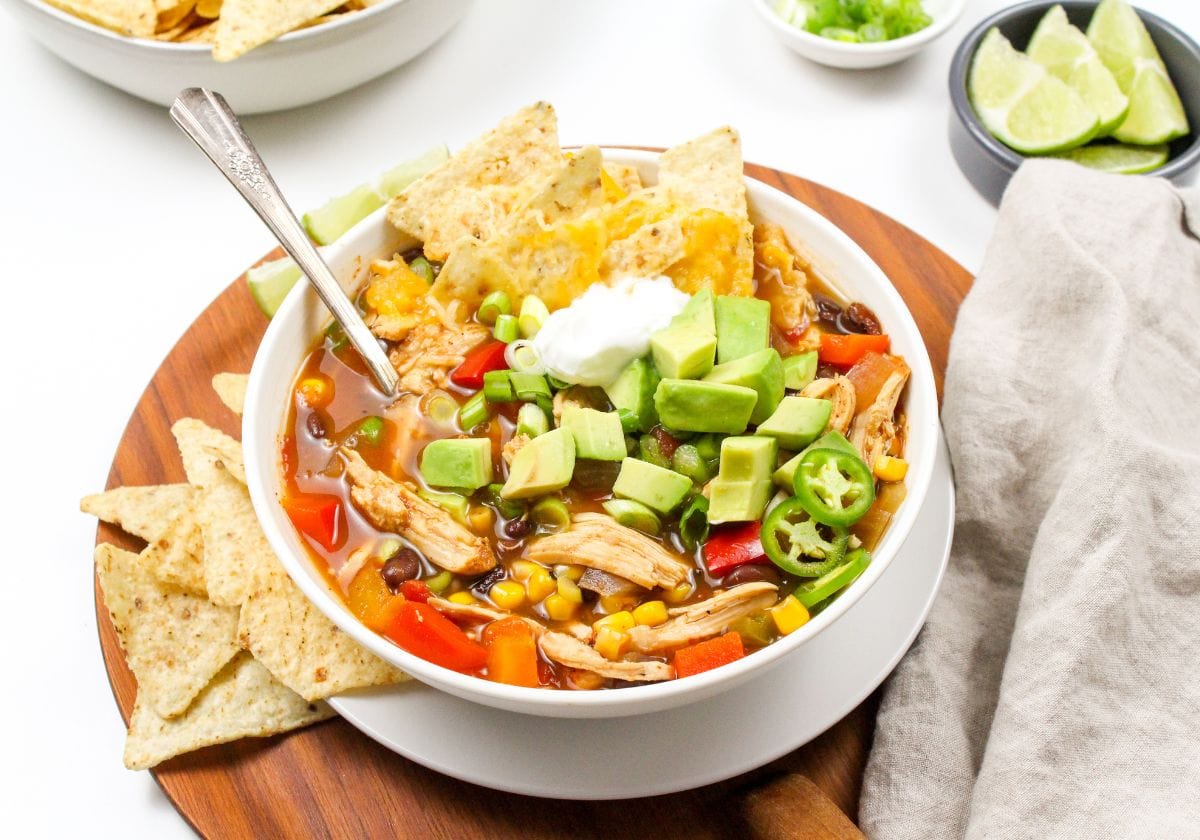 bowl of taco soup with diced avocado and tortilla chips on top