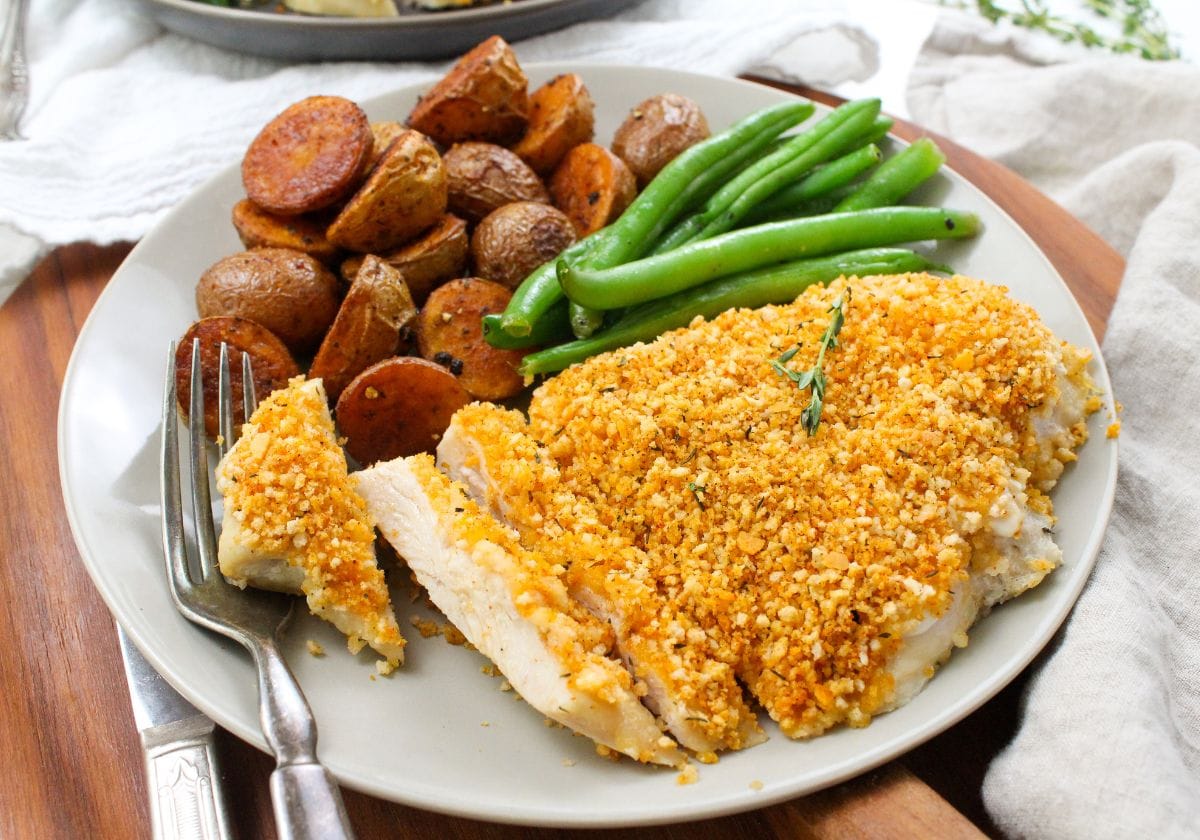 crispy baked panko crusted chicken on a plate with roasted potatoes and green beans