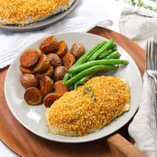 crispy panko roasted chicken breast on a plate with roasted potatoes and green beans