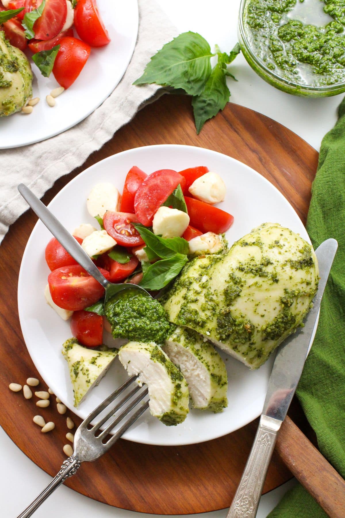 pesto chicken sliced on a plate with tomato and mozzarella salad