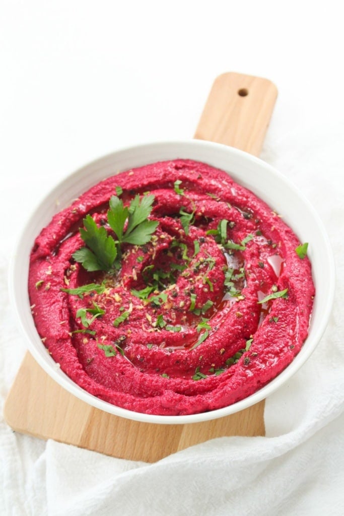 beet and tahini hummus in a bowl with herbs