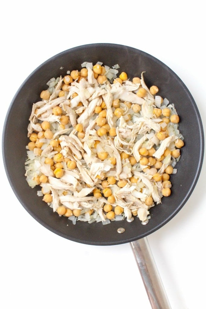 onion, garlic, chicken, quinoa, and chickpeas in a skillet