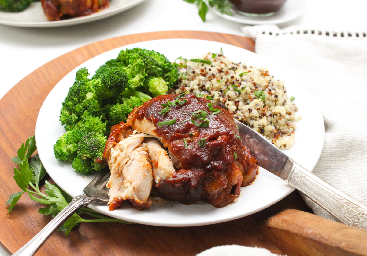 slow cooker BBQ chicken thigh on a plate with broccoli and quinoa