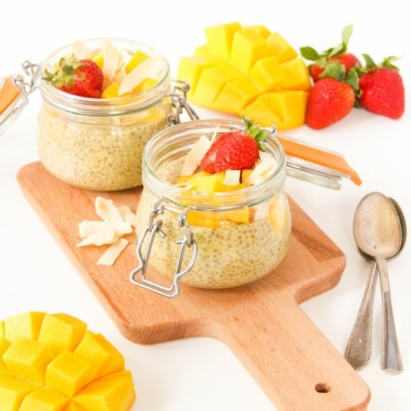 mango chia pudding with strawberries on a wooden platter