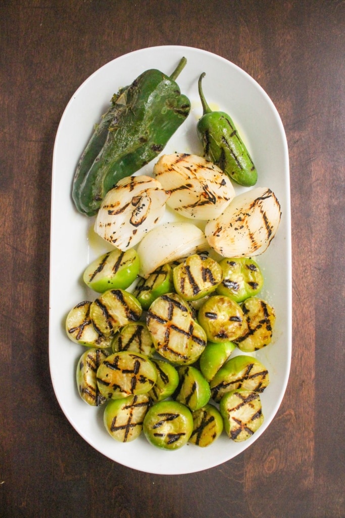 charred tomatillos, poblano peppers, jalapeno peppers, and onions on a large platter