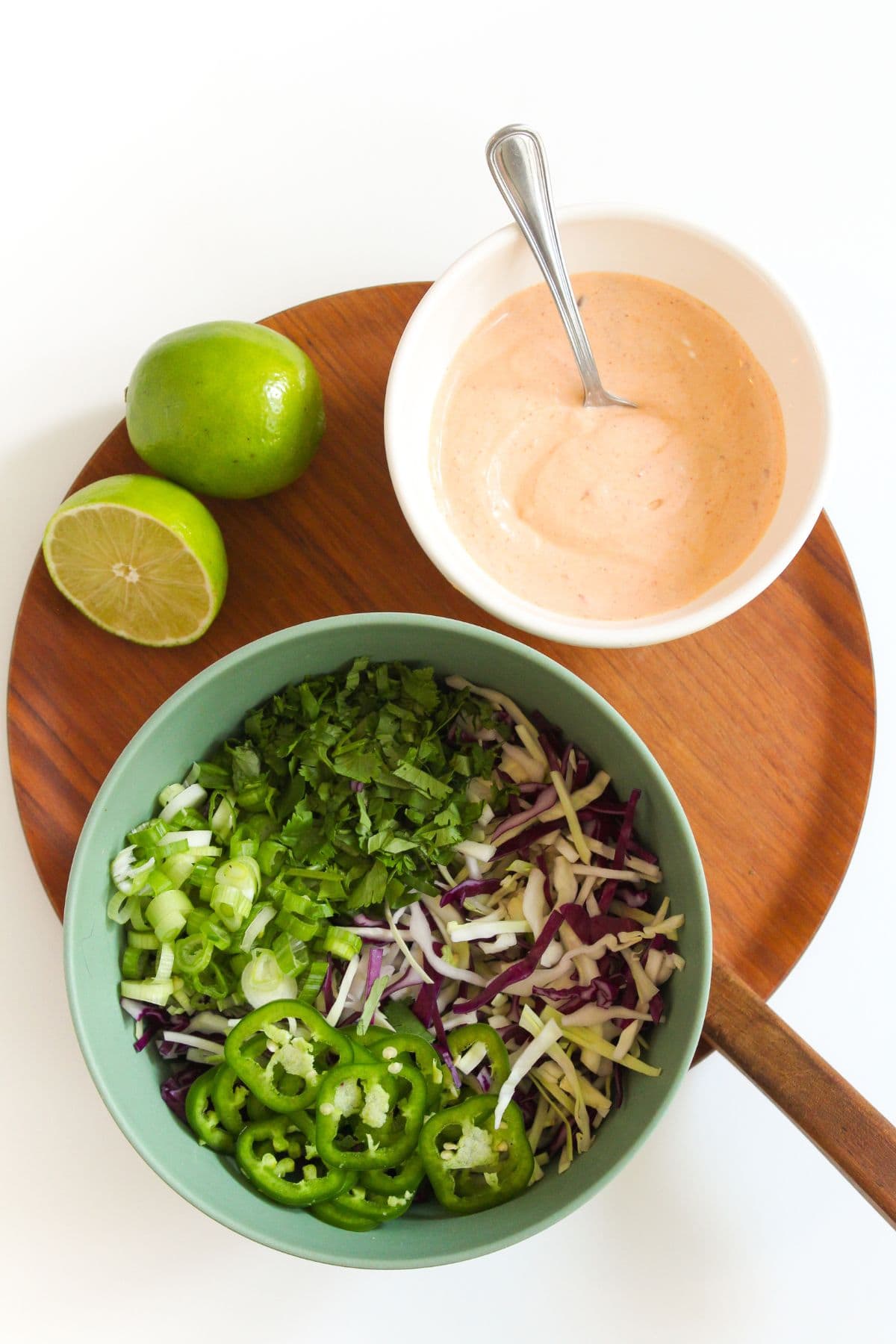 cabbage jalapeno slaw in a bowl with chipotle crema and limes