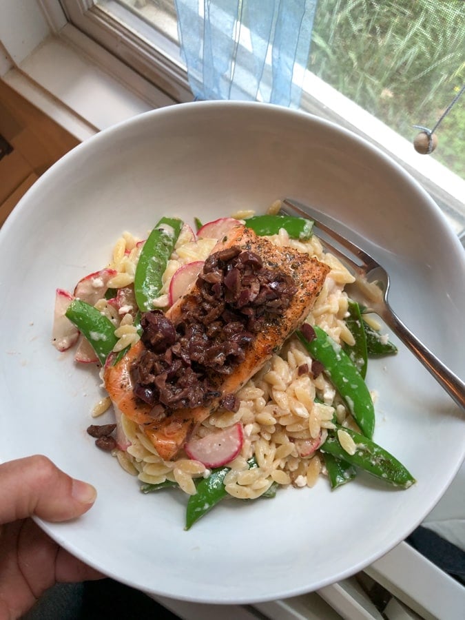 salmon in a bowl with orzo and olives