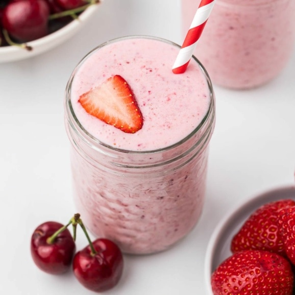 strawberry cherry smoothie with lemon in a mason jar with a striped straw