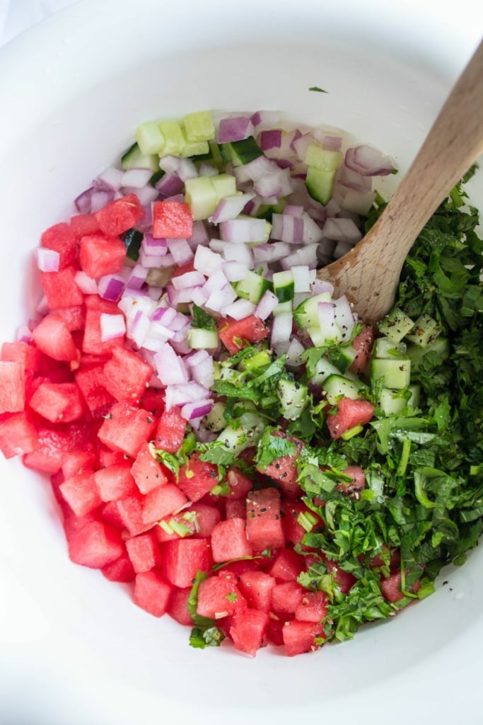 lime juice, watermelon, cucumber, red onion, mint, and cilantro in a bowl