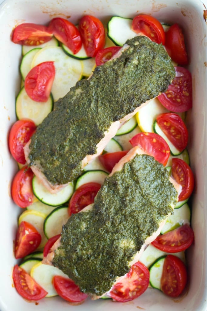 baked salmon with pesto sauce over sliced vegetables