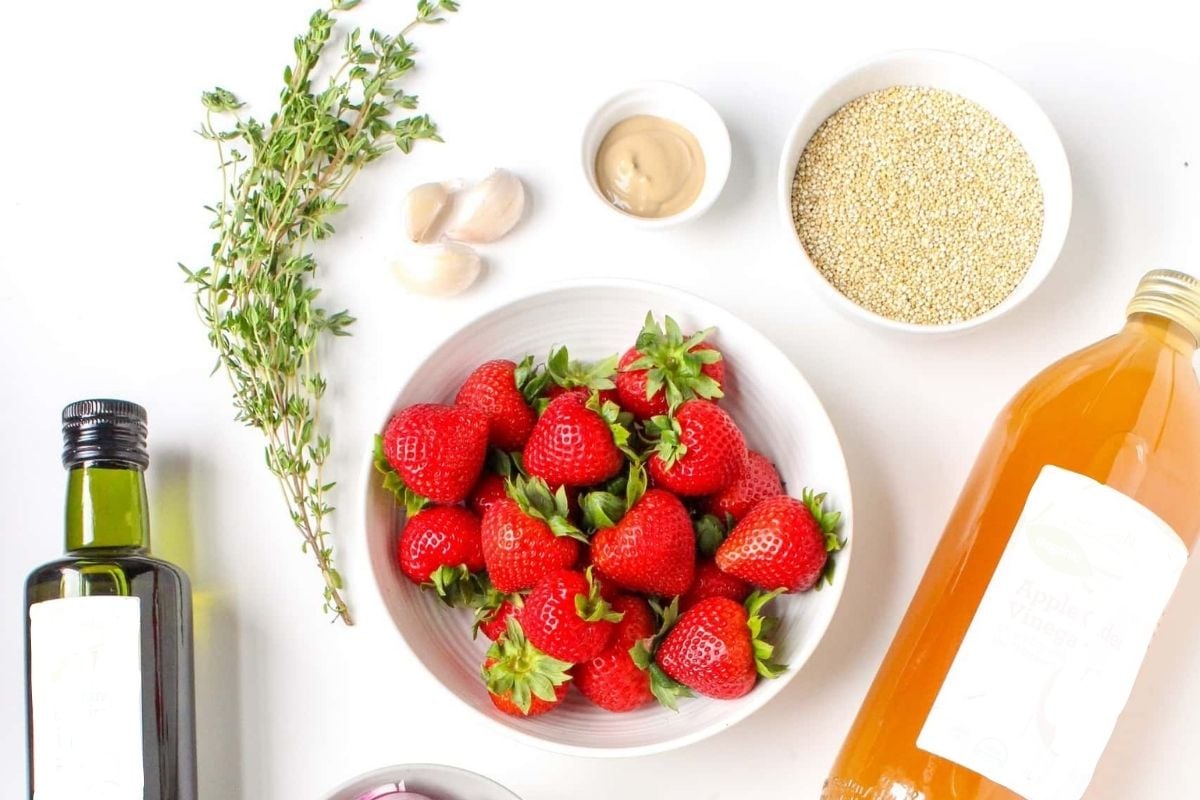 bowl of strawberries with dijon mustard, garlic cloves, herbs, olive oil, and apple cider vinegar