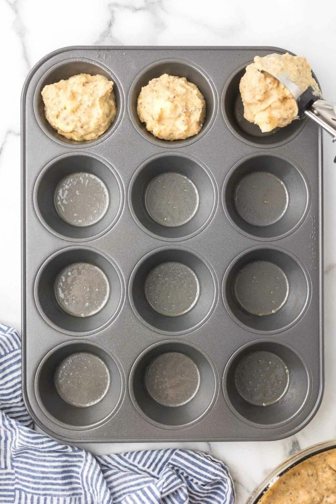 muffin batter being scooped into a muffin tin